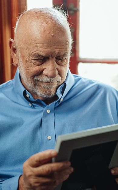 old man looking at a photo frame