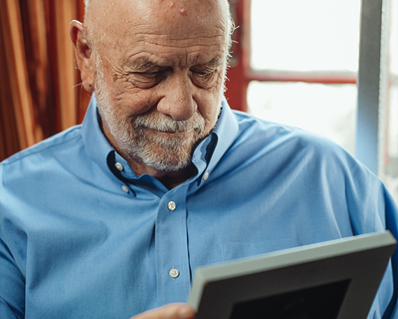 old man looking at a photo frame