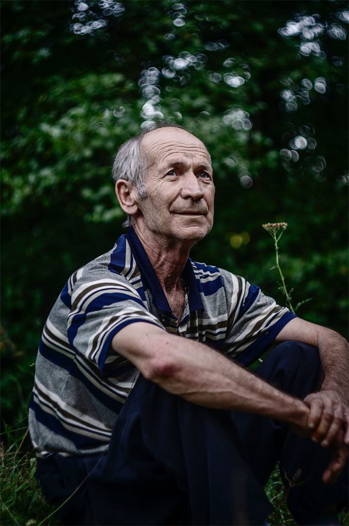 old ma sitting in a garden